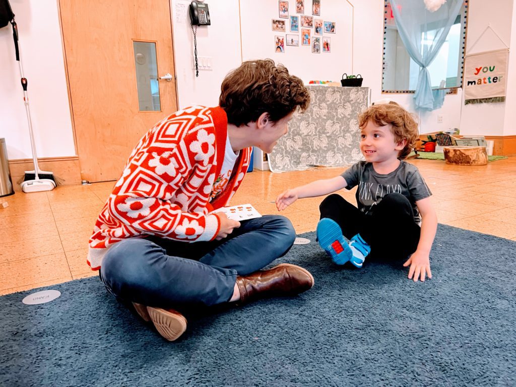 A teacher talking to a child on the floor