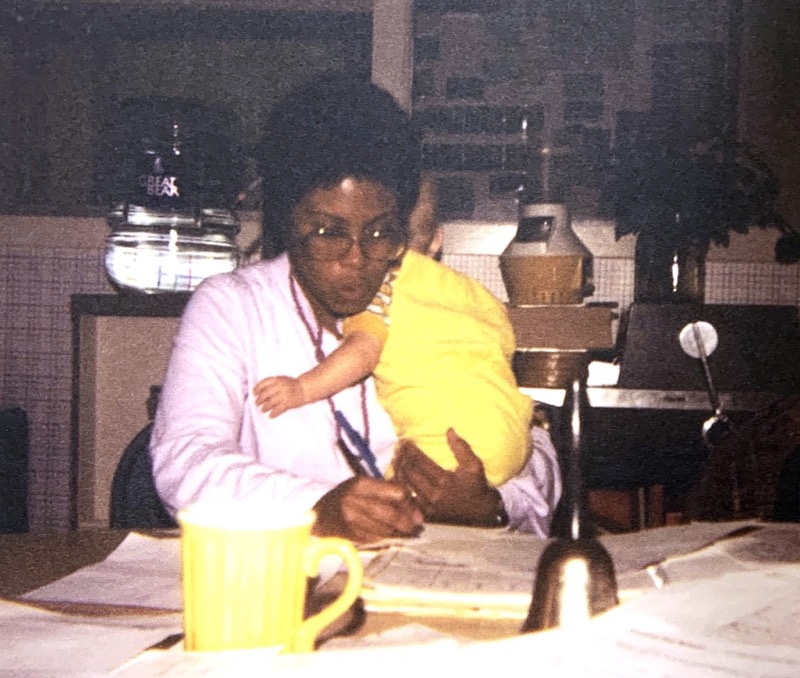 teacher holding infant while writing notes